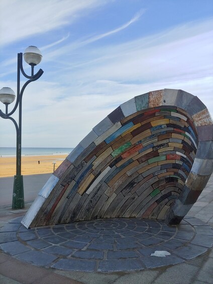 A curved mosaic bench with a street lamp beside it, overlooking a beach. 2