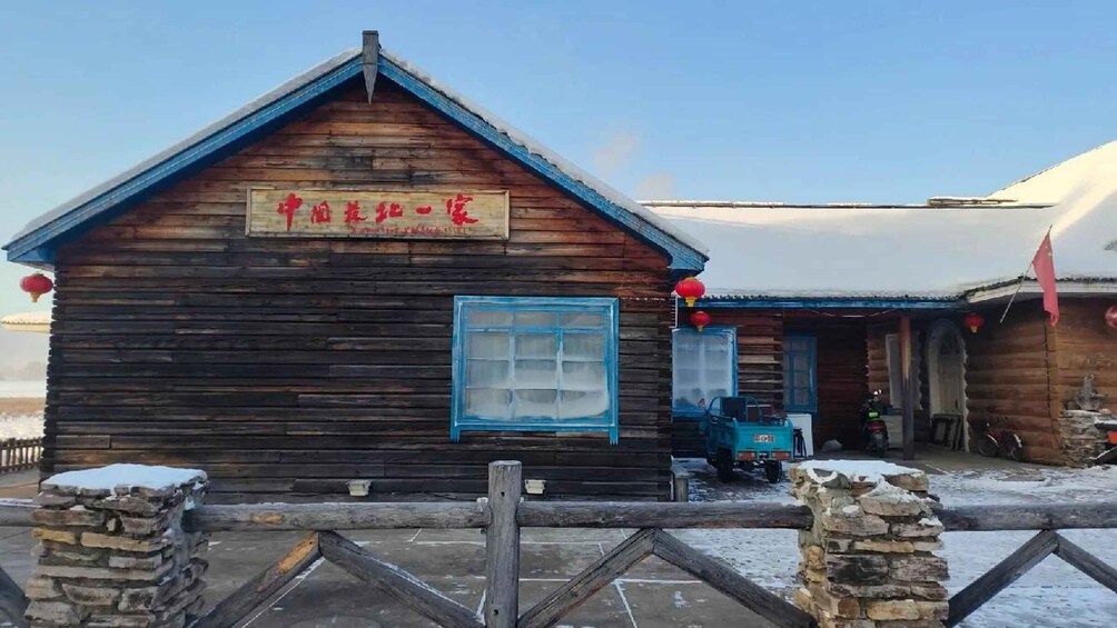 A wooden building with a blue window and a sign in a foreign language. 1