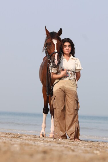 A person standing on a beach with a horse. 5