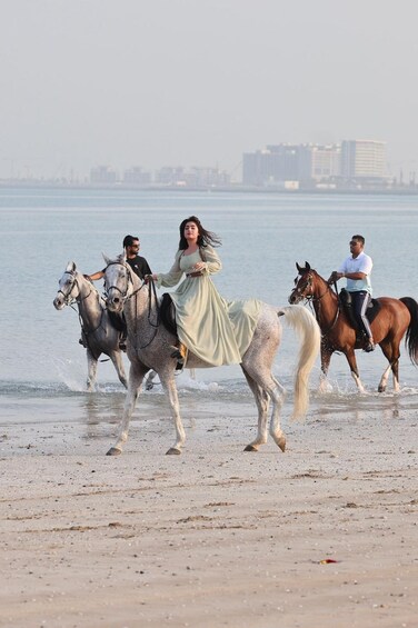 A beach with people riding horses. 4