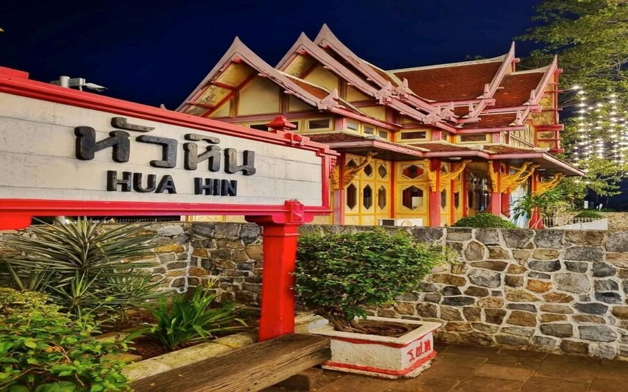 A traditional building with a sign reading 'HUA HIN' and a stone wall with plants. 3