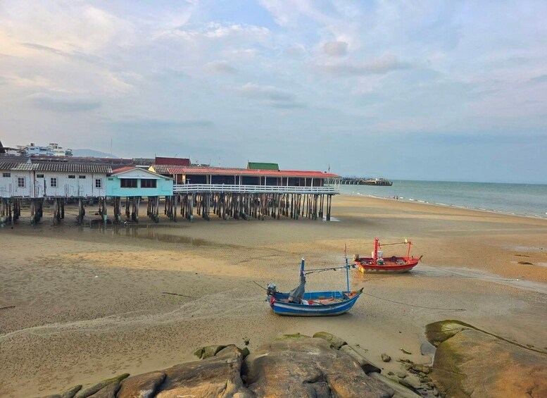 A beach with wooden houses, a pier, and boats. 5
