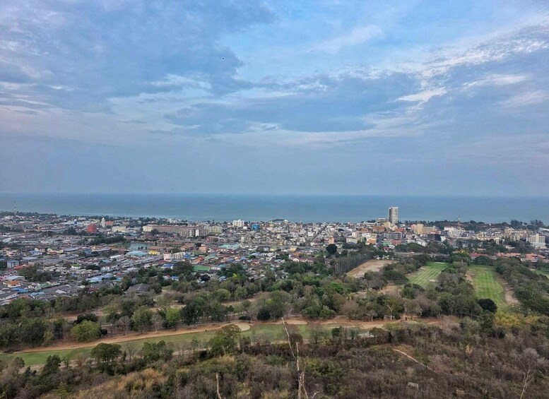 A coastal cityscape with a prominent high-rise building, dense residential areas, and a mix of greenery. 2