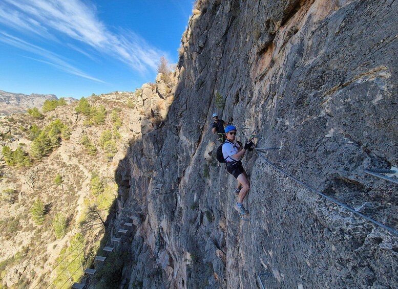 A person rappelling down a rocky cliff with a harness and ropes. 1