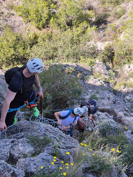 Two people rappelling down a rocky slope with ropes and helmets. 2