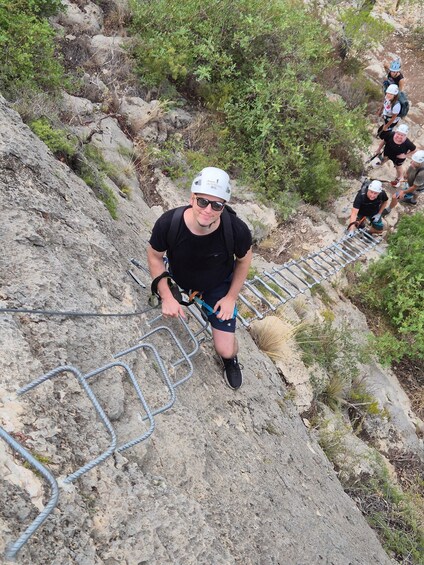 A person climbing a rocky trail with metal handrails. 4