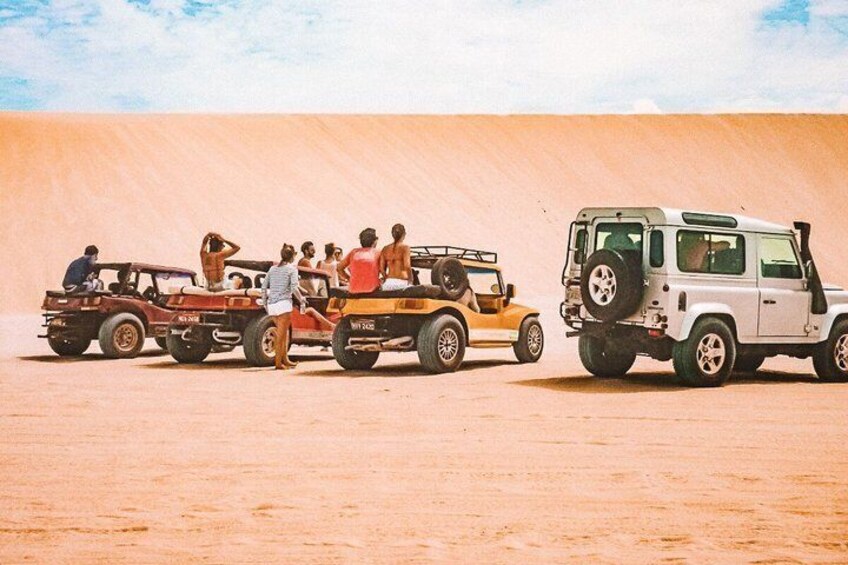 A desert landscape with three vehicles and people. 5