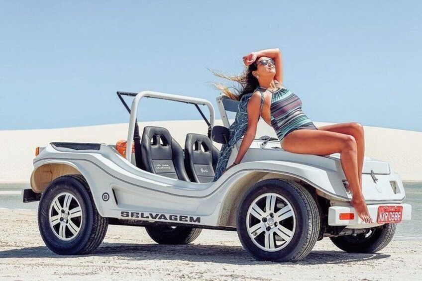 A convertible car with 'SALVAGEM' branding parked on a sandy beach. 1