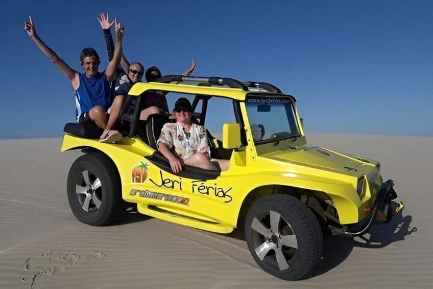 A yellow off-road vehicle with passengers on a sandy terrain. 3