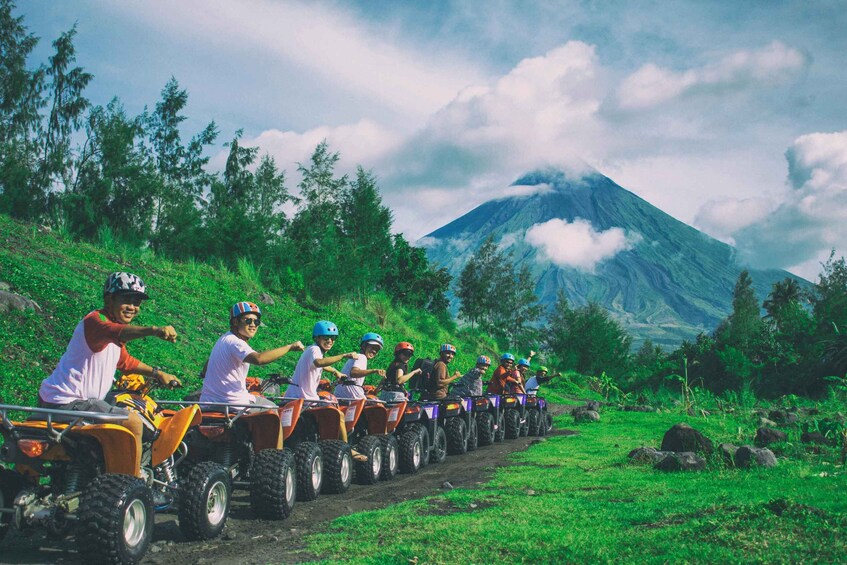 A group of people on ATVs on a dirt path with a mountain in the background. 2