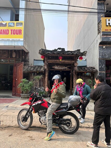 A person on a red motorcycle, another on a scooter, and a building with a traditional entrance. 2