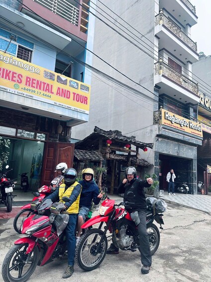 Three people on motorcycles in front of a building with a sign for 'HAGIANGGO HOSTEL'. 5