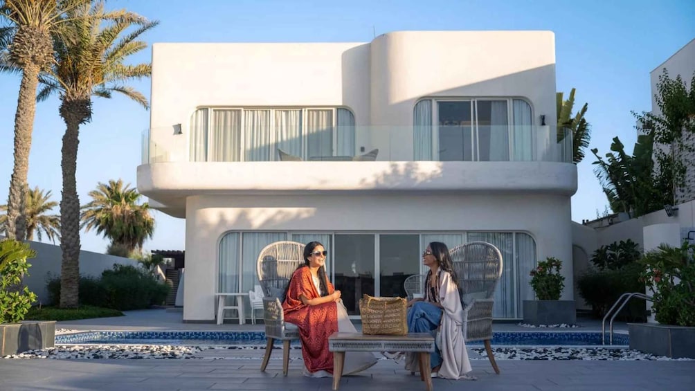 A modern two-story house with a balcony, palm trees, and a swimming pool. 1