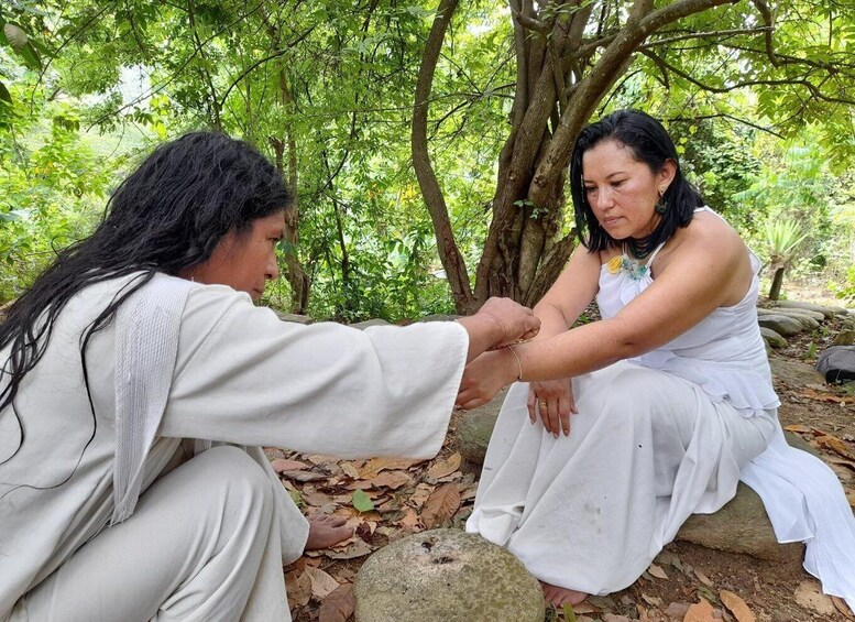 Two individuals sitting on a rock in a forested area. 5