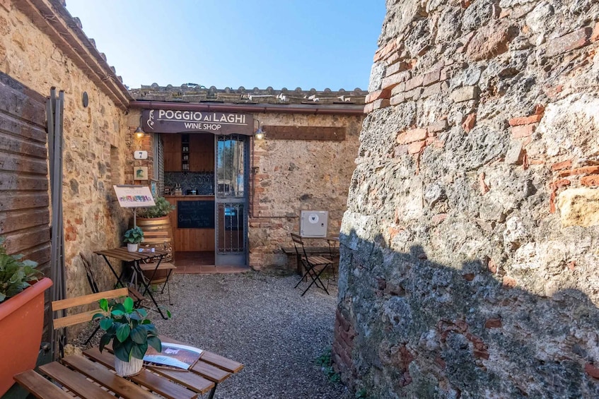 A wine shop named 'Poggio Al Laghì' with outdoor seating and a rustic stone wall. 4