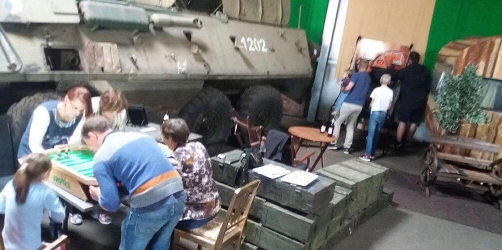 A group of people playing table football in front of a military tank. 4