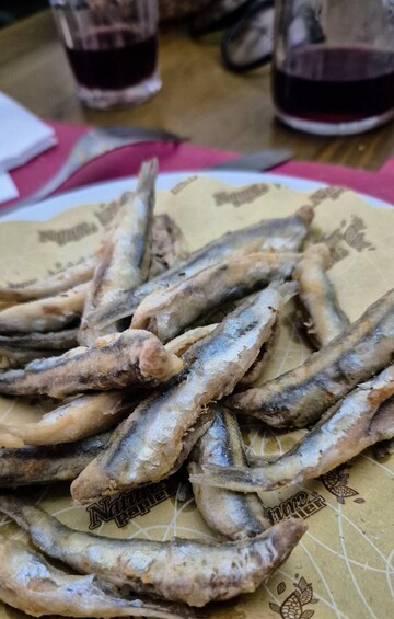A plate of fried fish with a patterned paper underneath. 4