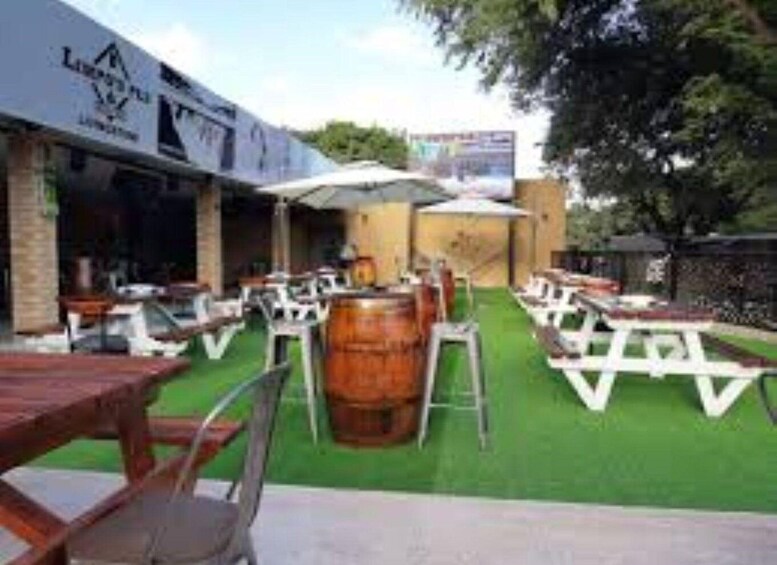 An outdoor dining area with tables and chairs, a wooden barrel, and a building with signage. 4