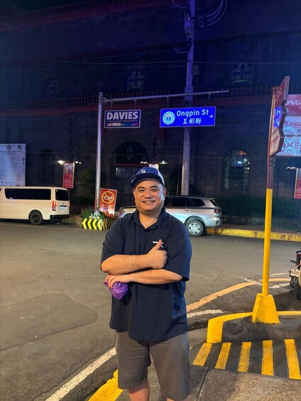 A person standing on a street corner with a building in the background, a sign for Ongpin St, and a DAVIES sign. 4