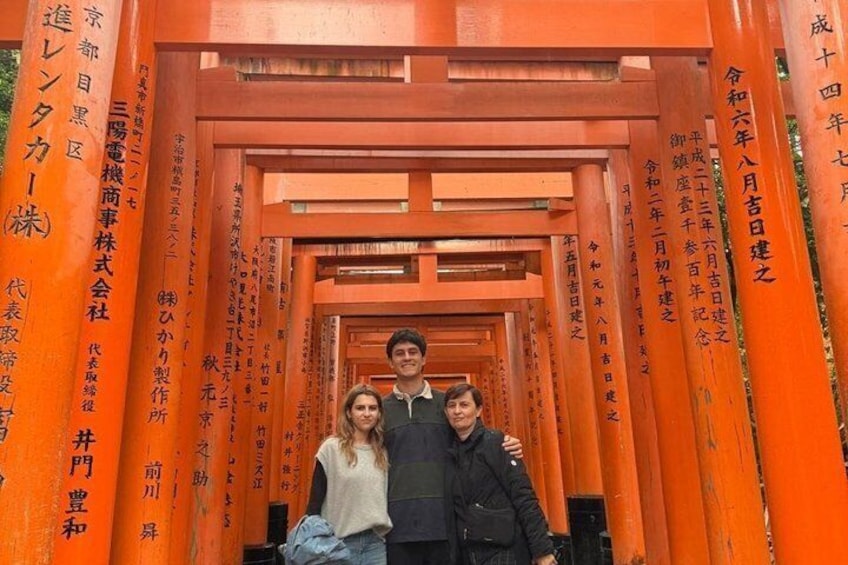 A group of people standing in front of a traditional Japanese torii gate. 4