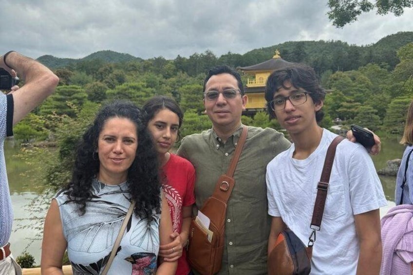 A group of people standing by a body of water with a temple in the background. 3