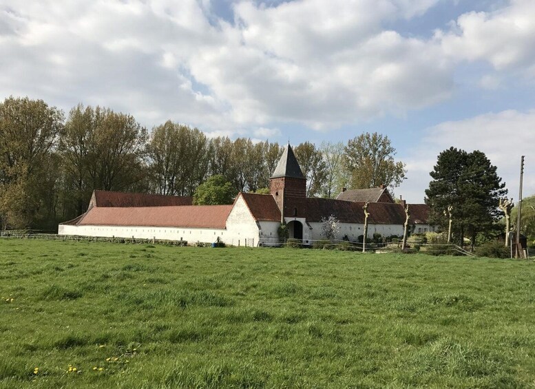 A church with a red roof and a bell tower, surrounded by a green field and trees. 5