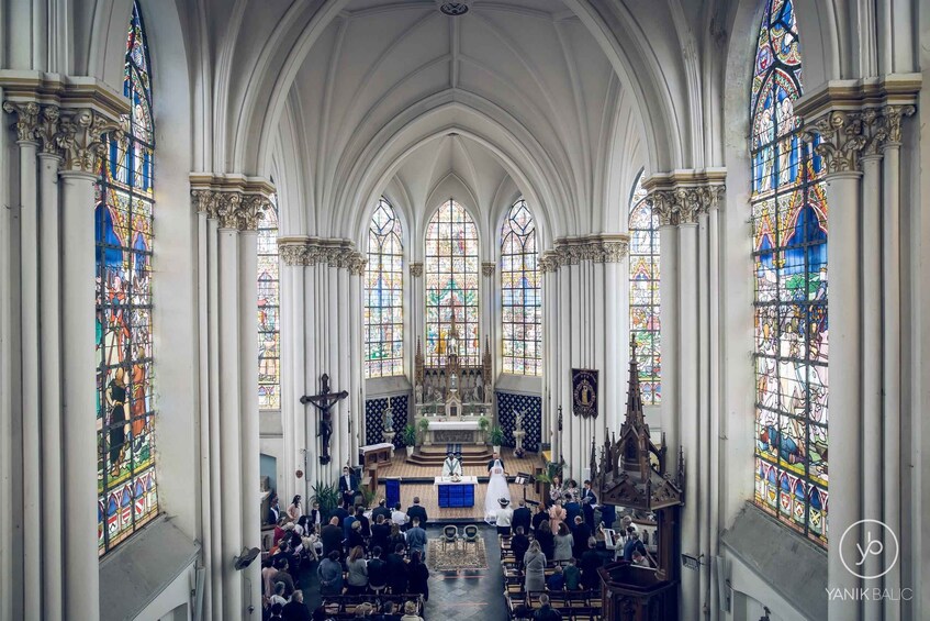 A church interior with stained glass windows, pews, and a central altar. 4