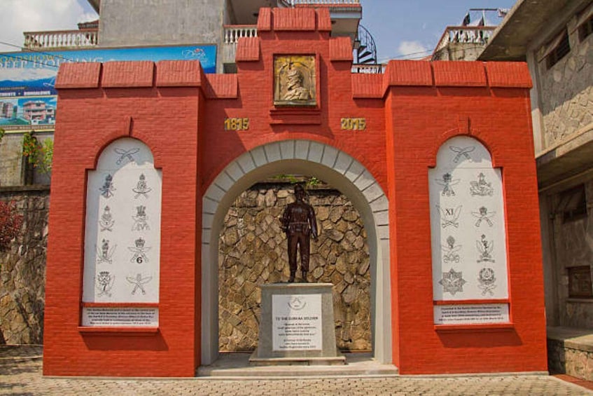 A red brick monument with a statue, featuring inscriptions and a plaque. 4
