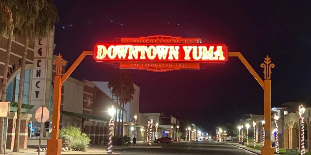 A nighttime street scene with a prominent 'Downtown Yuma' sign. 1