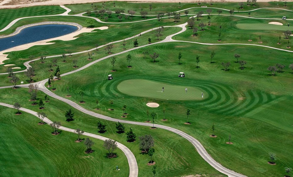 A golf course with winding paths, sand bunkers, and a pond. 2