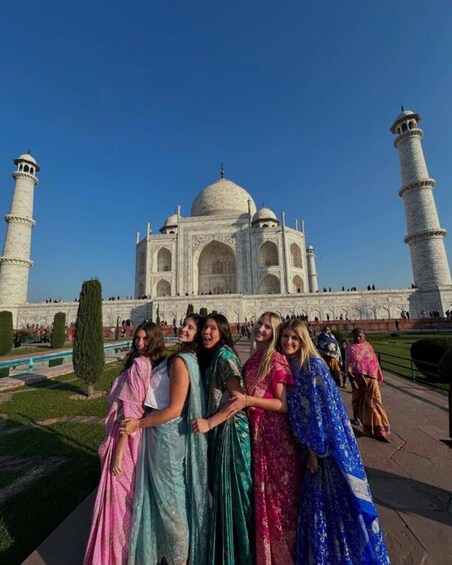 A group of people in traditional attire standing in front of the Taj Mahal. 4