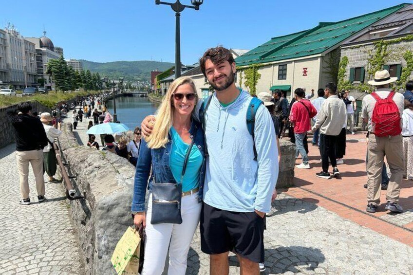 A couple standing by a historic stone wall with a river in the background. 3