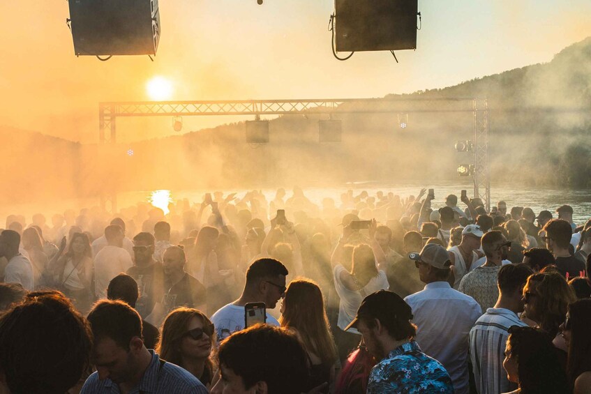 A crowd at a waterfront event with a bridge in the background. 2