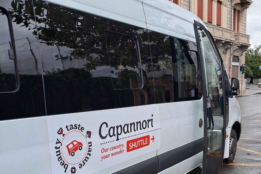 A white shuttle bus with 'Capannori' and 'taste' logos, parked in a lot. 4