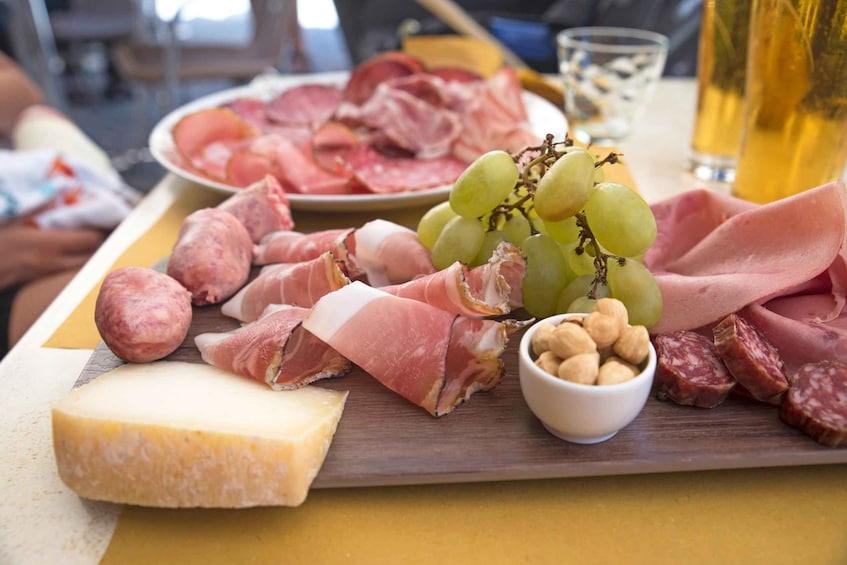 A charcuterie board with various meats, cheese, grapes, and nuts. 5