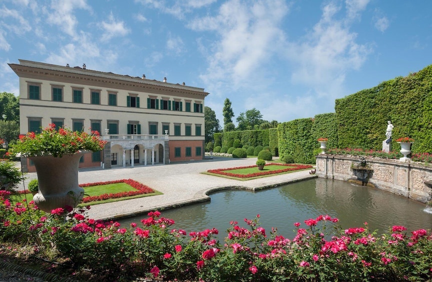 A classical building with a courtyard, a fountain, and a well-manicured garden with roses. 1