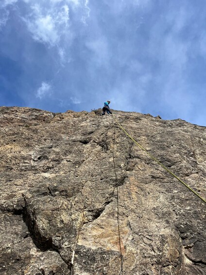 A person climbing a rocky mountain with a clear sky. 1