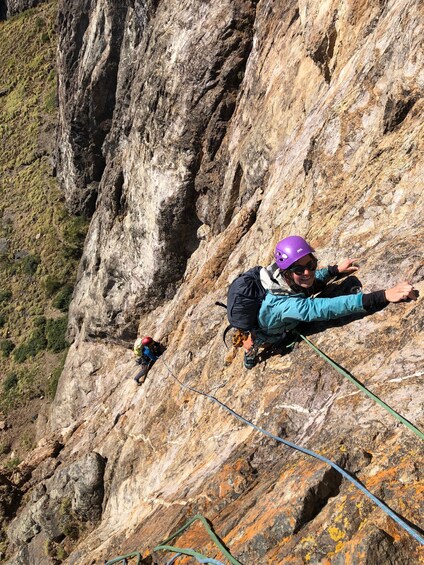 A person rappelling down a rocky cliff with a harness and helmet. 3