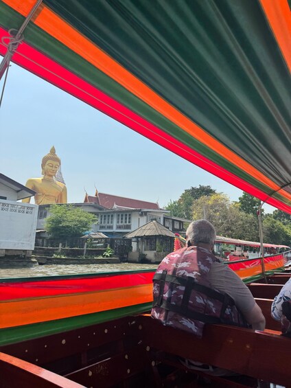 Henkilö veneessä, taustalla suuri kultainen Buddha-patsas. 5