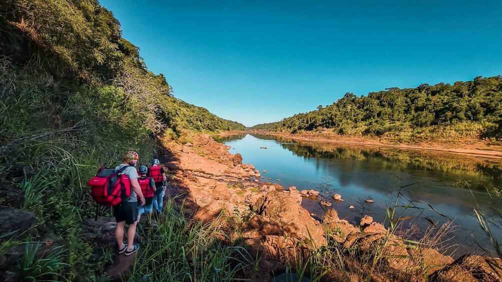 A river with hikers on a rocky path. 3