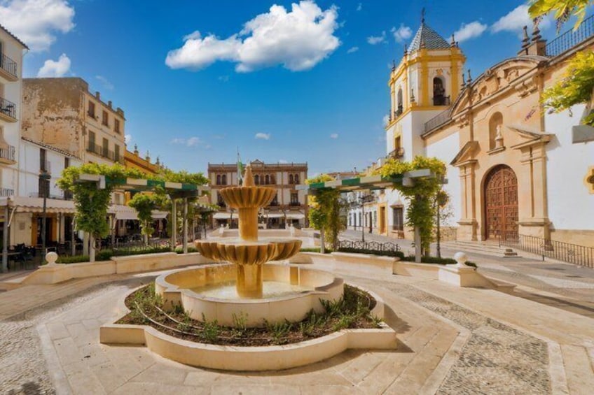 A historic plaza with a central fountain, surrounding buildings, and a bell tower. 4