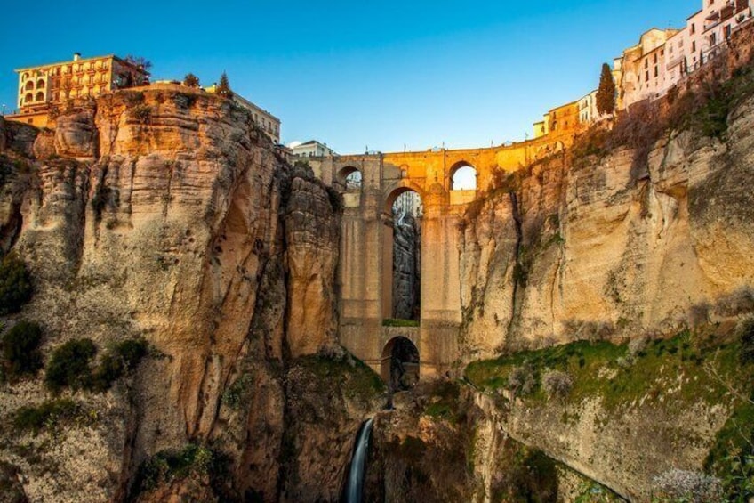 A bridge with a large arch and buildings on cliffs. 2
