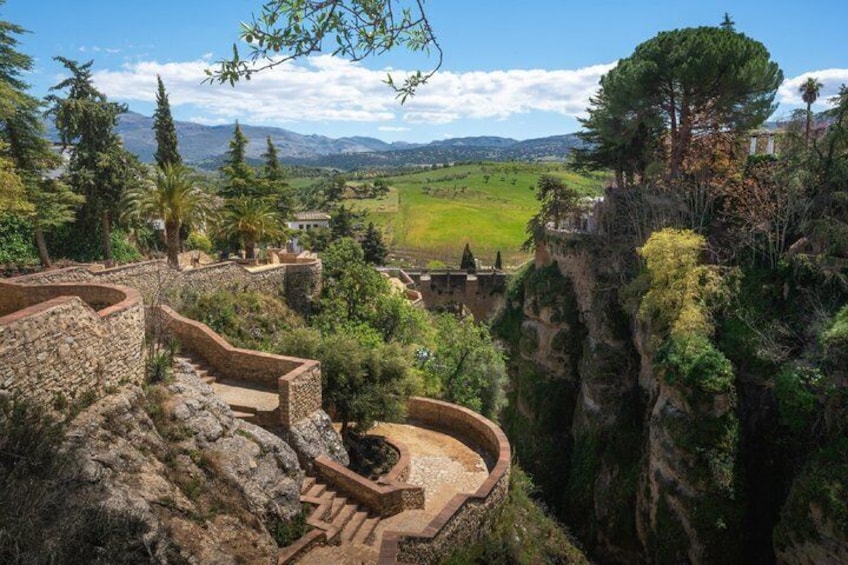 Ancient stone steps, a cliffside, and a distant view of a valley. 3