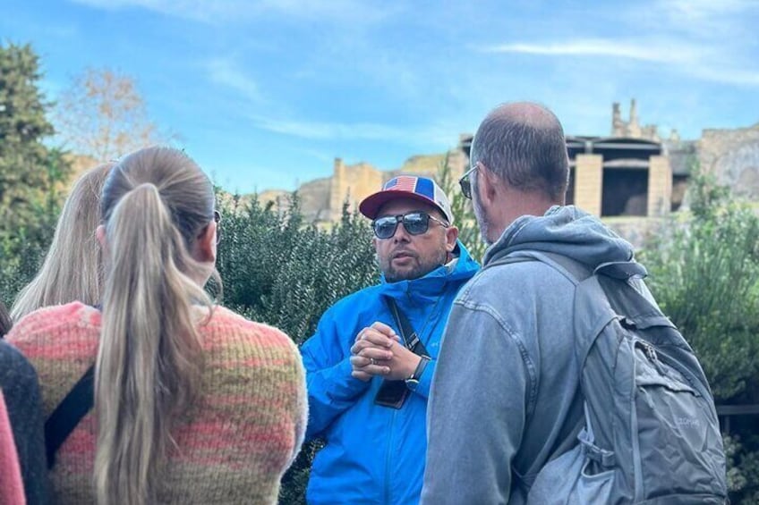 Three people standing outdoors, one in a blue jacket and cap, another in a grey jacket, and a third in a pink sweater. 4