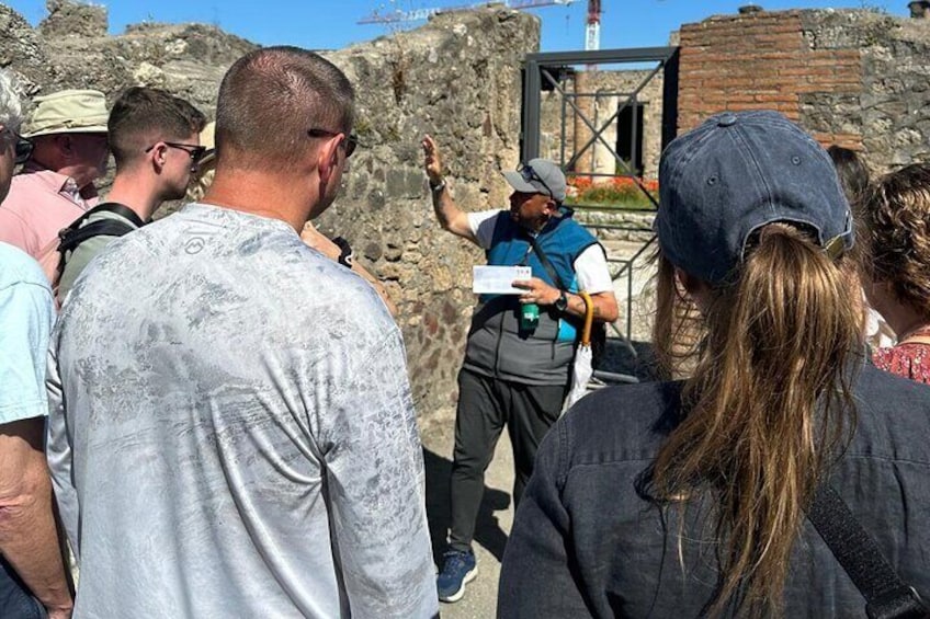 A group of people observing ruins with a guide pointing out features. 3