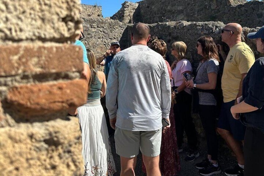 A group of people standing near a stone wall, possibly at a historical site. 2