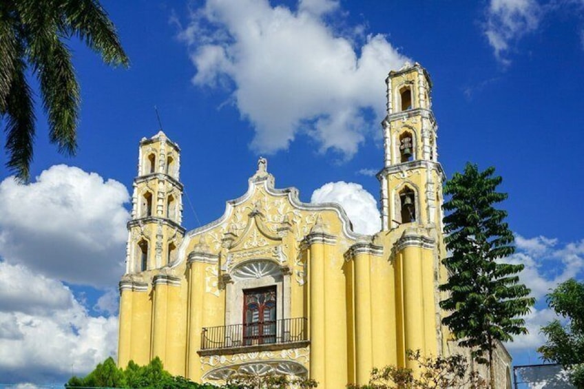 A yellow church with two bell towers and a balcony. 4
