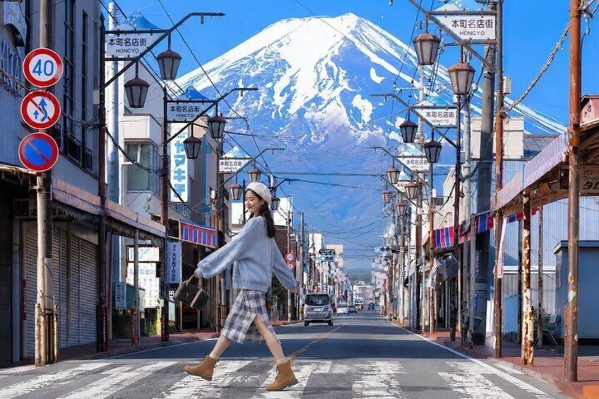 A street with a person crossing, shops, and a snow-capped mountain in the background. 4