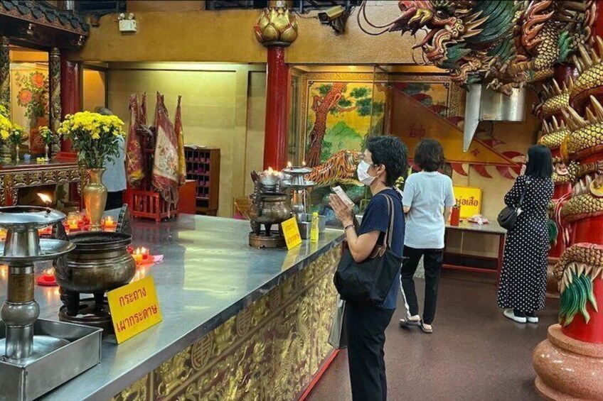 A temple interior with altars, incense, and visitors. 1