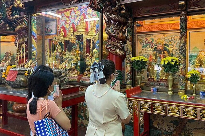 A temple interior with ornate decorations, statues, and floral arrangements. 3